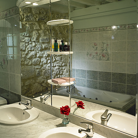 Een comfortabele badkamer met bubbelbad en dubbele wastafel